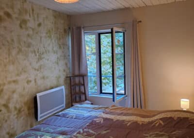 Grande chambre avec lit double et porte donnant sur l’extérieur