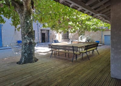 Table et bancs sous le préau ombragé par un platane